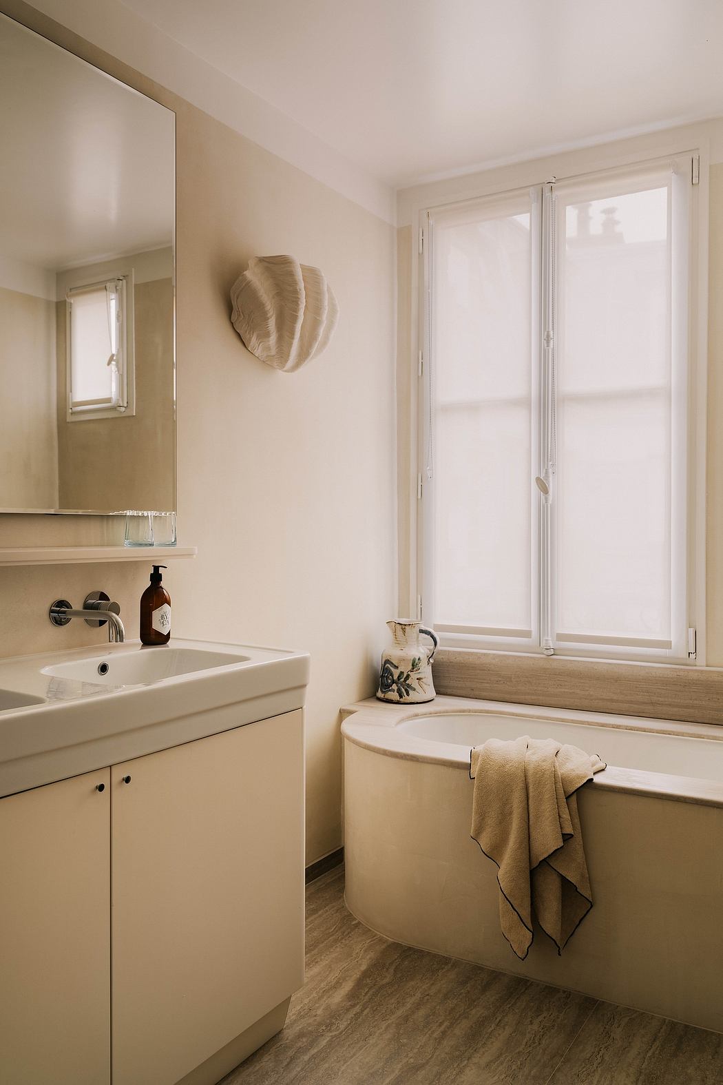 The image shows a modern bathroom with a sink, mirror, and a bathtub. The room has a minimalist, neutral-toned design.