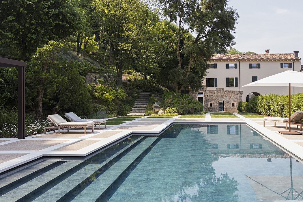 Elegant outdoor pool area surrounded by lush greenery and a modern villa.