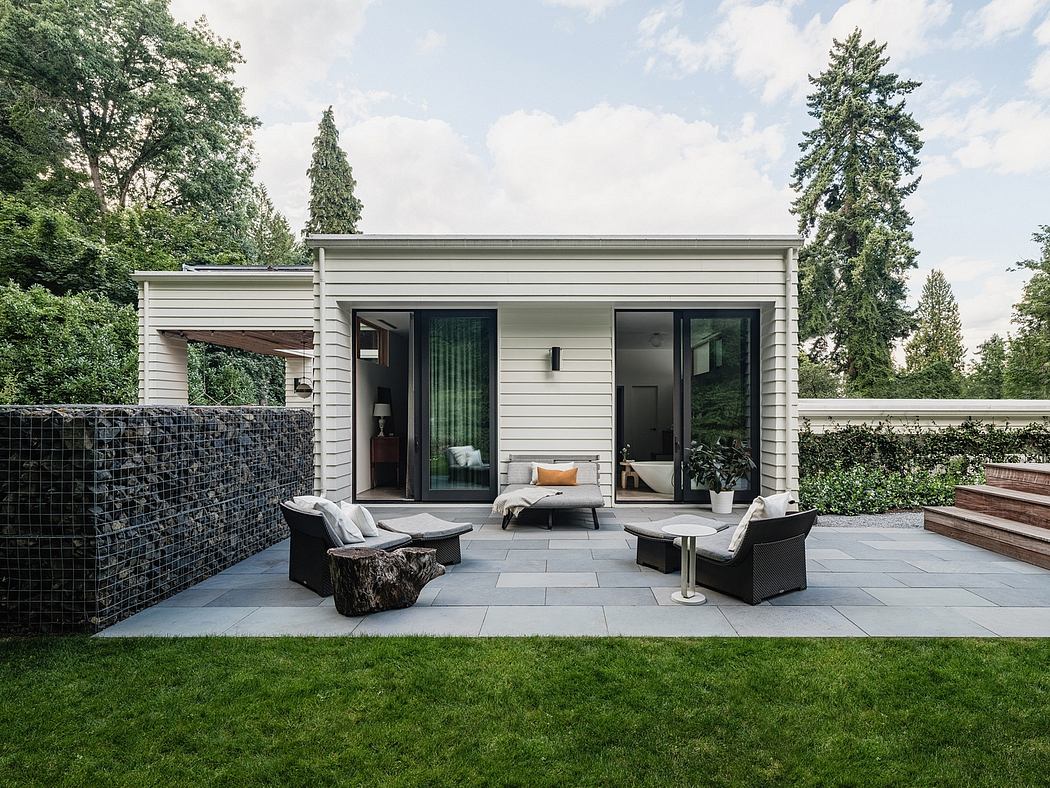 A modern, open-concept outdoor living space with a gray siding exterior and large glass doors.