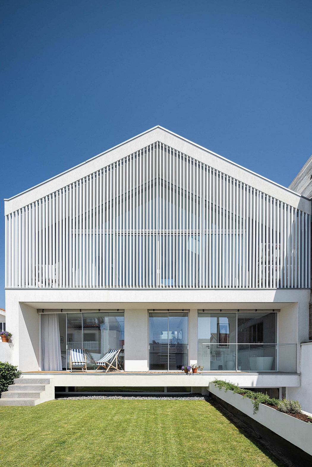 A modern, minimalist home with a striking exterior featuring vertical white panels and large windows.