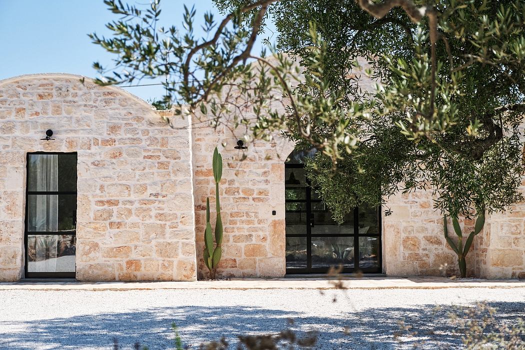 Stone walls, arched windows, and lush olive trees create a serene Mediterranean atmosphere.