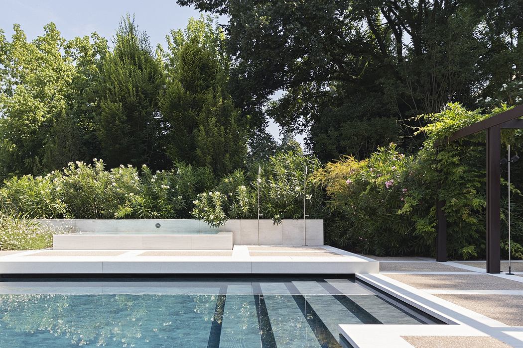 A modern pool design with clean lines, concrete elements, and lush greenery surroundings.