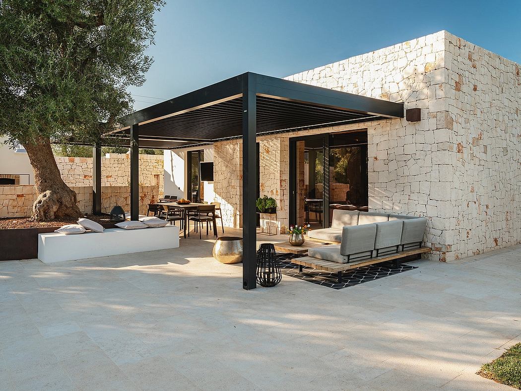 Sleek, modern outdoor living space with stone walls, metal pergola, and comfy furniture.