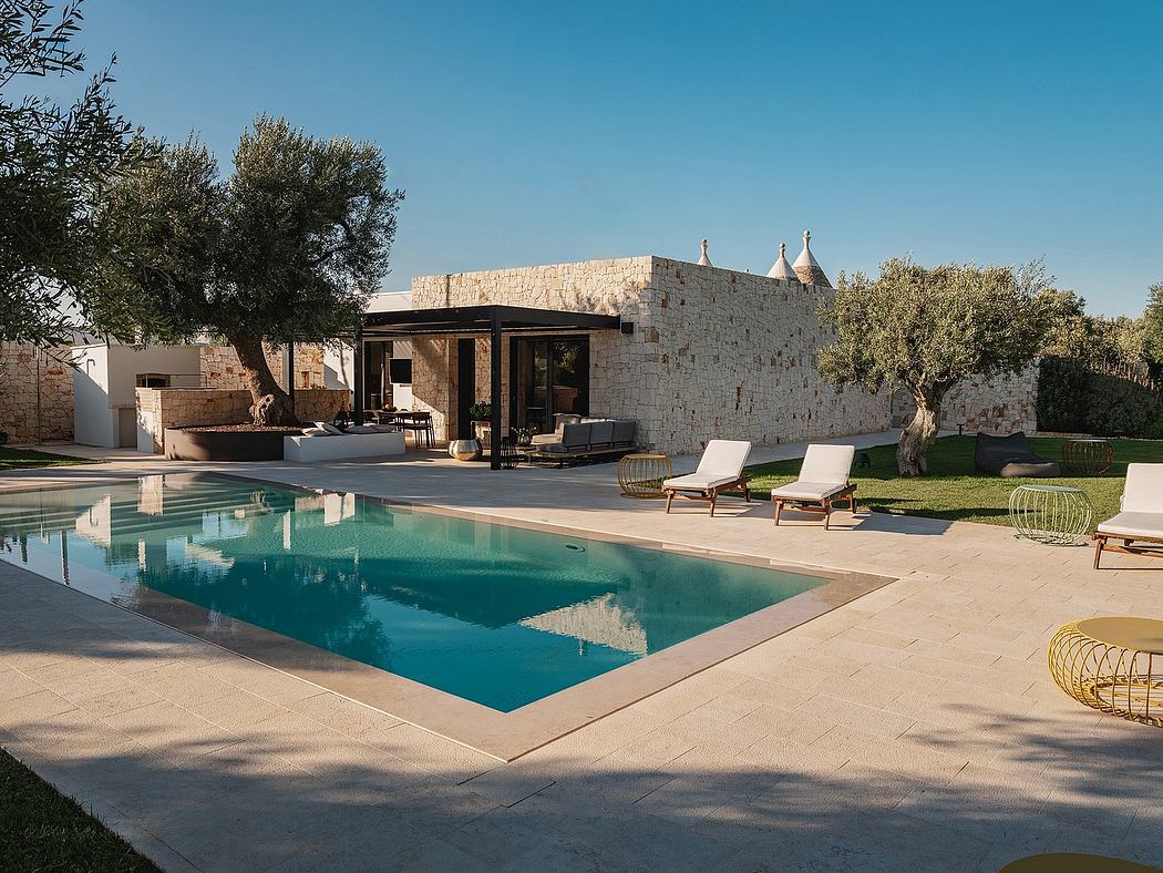 A luxurious outdoor poolside oasis with a stone villa, covered patio, and lush landscaping.