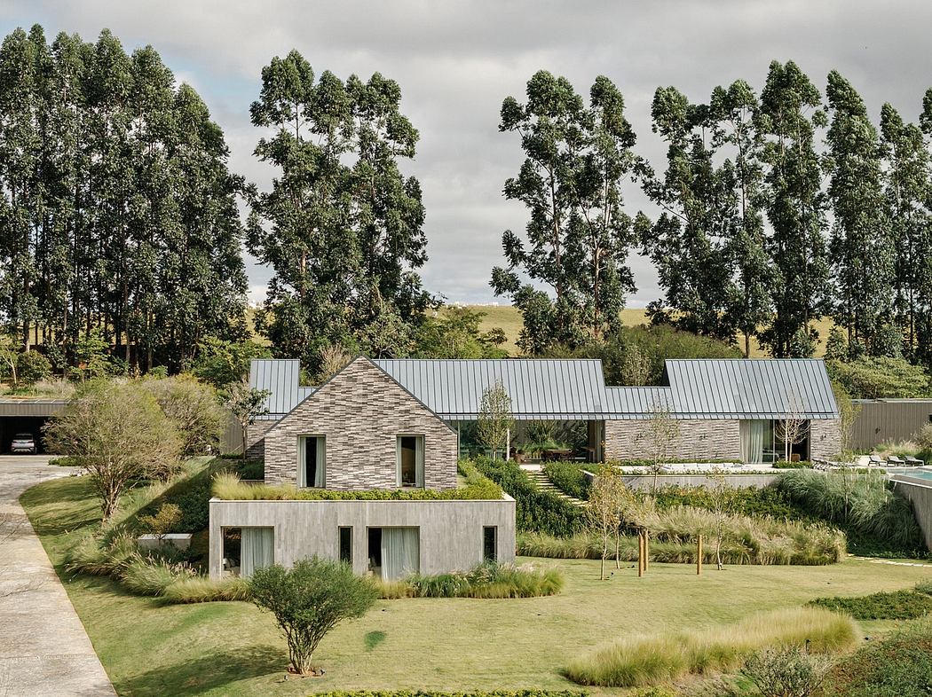 Modern stone and metal buildings with minimalist design nestled in lush, wooded landscape.