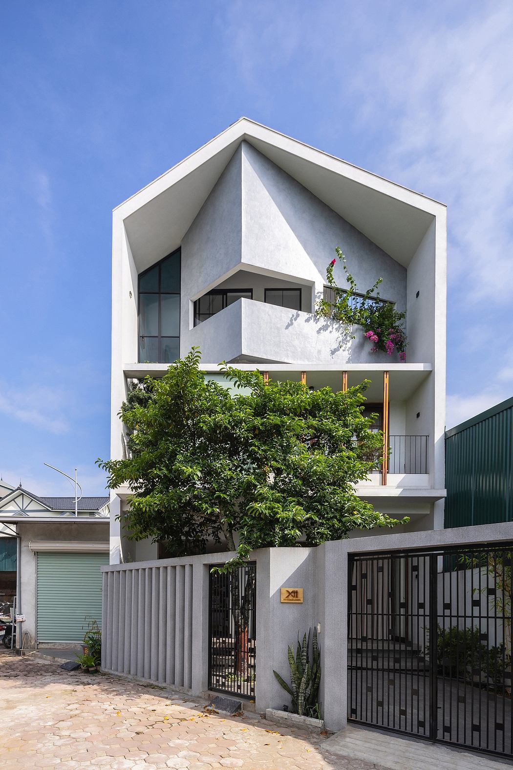 Modern, multilevel residential building with geometric facade, balconies, and lush vegetation.