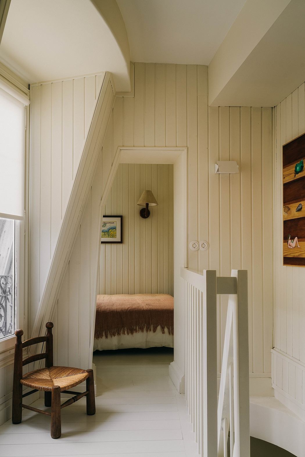 Cozy nook with wooden paneled walls, vintage chair, and glimpse of bedroom.