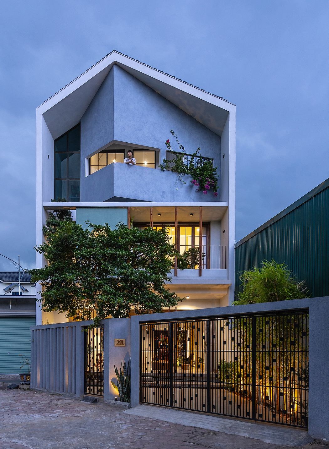 A multi-story modern house with an intricate facade, balconies, and a lush garden.