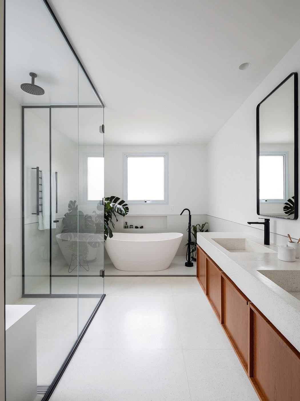 Sleek modern bathroom with freestanding tub, glass shower, and wooden vanity.