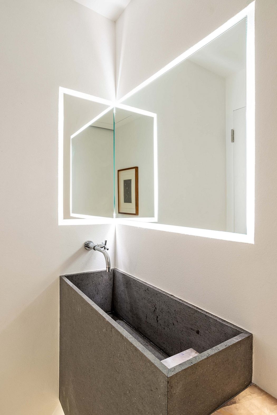 Contemporary bathroom design featuring a large angular mirror and sleek concrete sink.