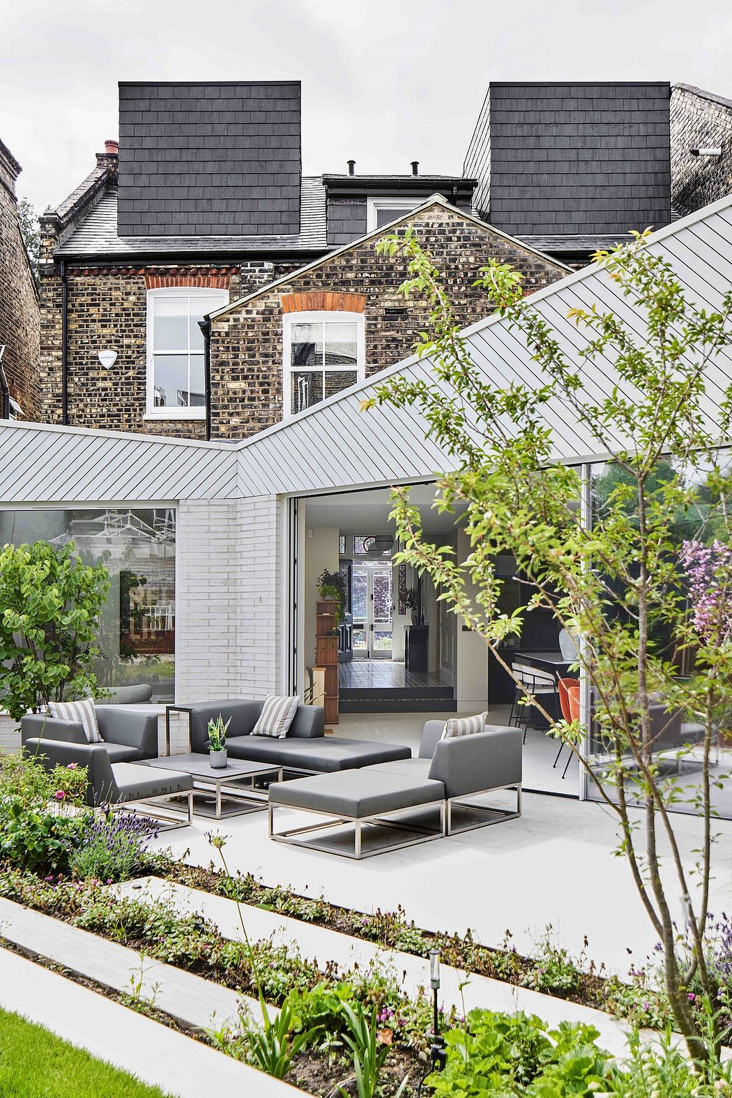 Modern brick building with gray sloped roofs and sleek outdoor furniture.