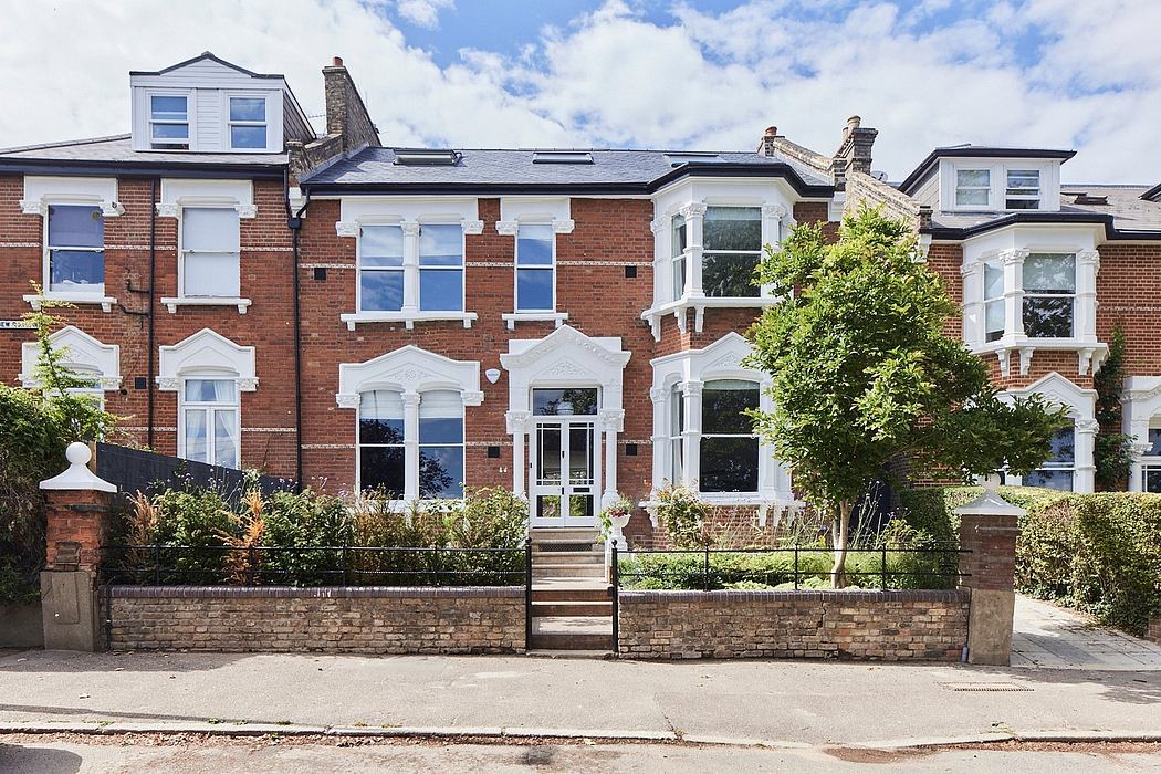 Elegant Victorian-style townhouse with ornate windows, brick facade, and landscaped yard.
