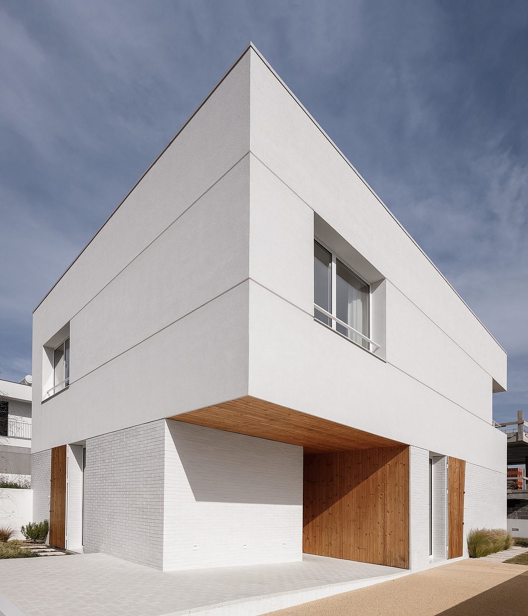 Minimalist white cubical structure with wood-paneled entryway and geometric windows.