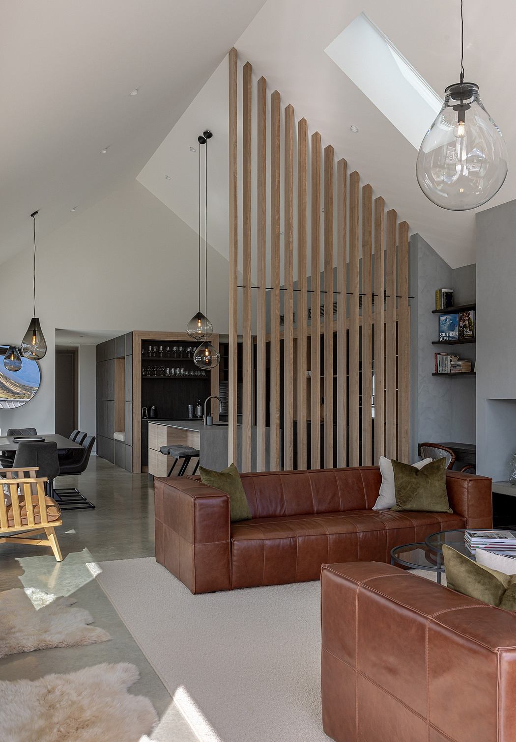 Modern open-plan living space with wooden slat feature wall, leather sofa, and pendant lighting.