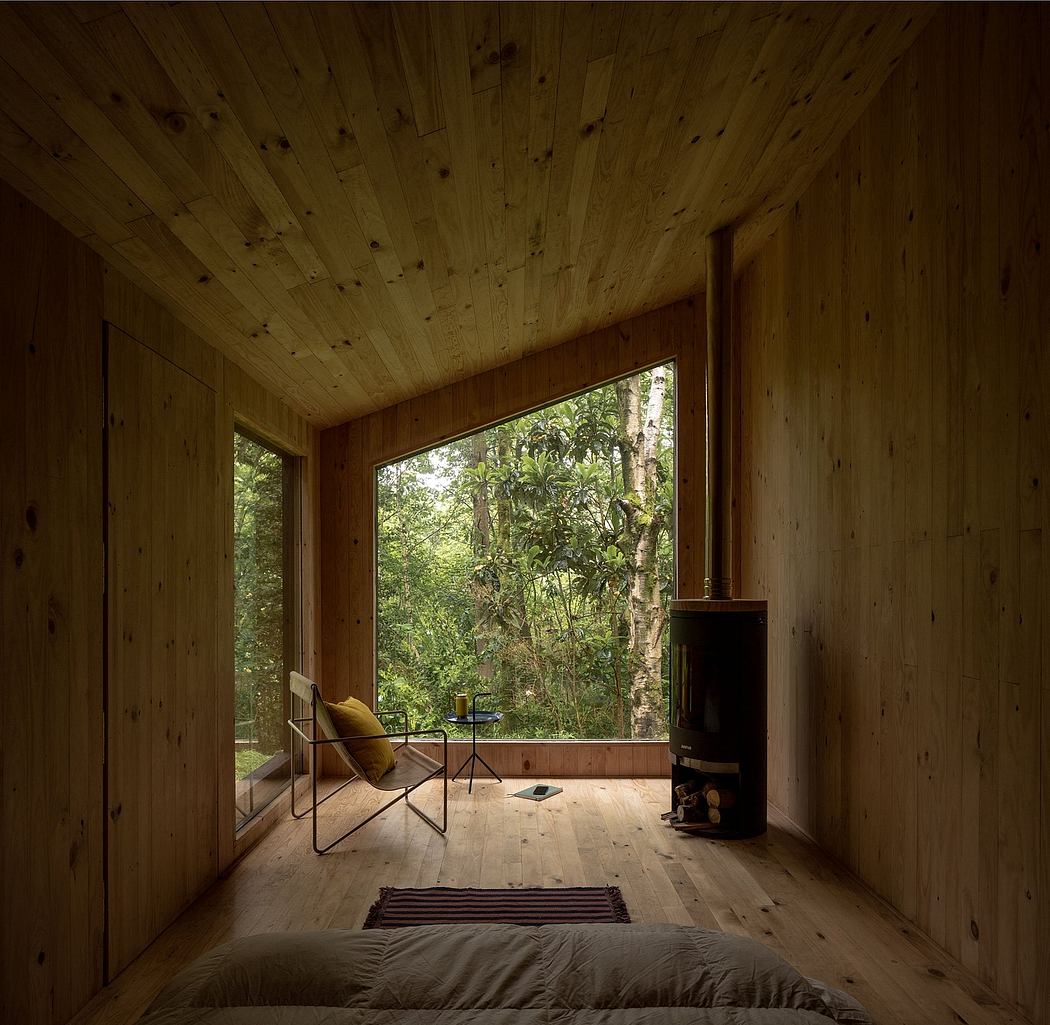 Rustic wood cabin interior with large picture window overlooking lush forest.