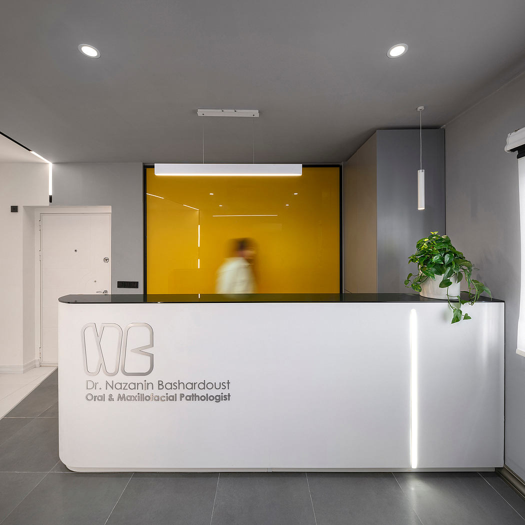 Modern reception desk with white surface, yellow accent wall, and minimal lighting in a professional office space.