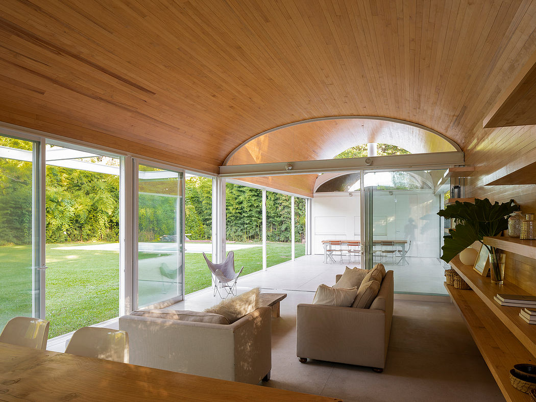 Cozy wood-paneled living space with arched windows overlooking lush greenery.