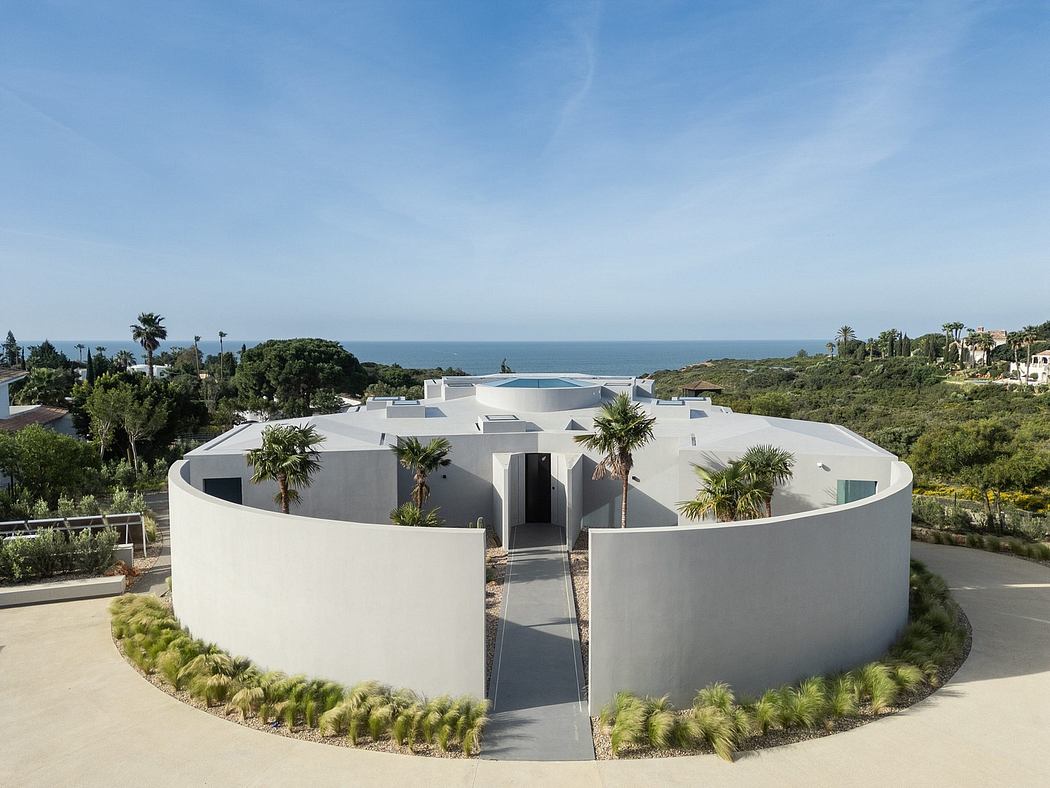 Striking modern circular building with lush palm trees and expansive ocean view.