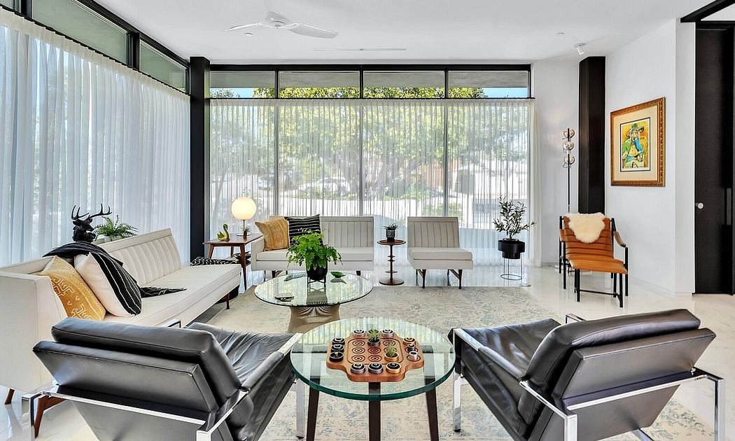 Spacious, light-filled living room with modern furnishings, large windows, and an artistic accent piece.