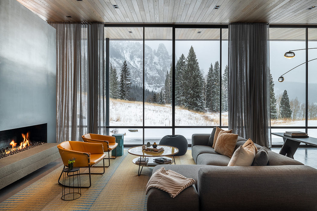 A cozy living room with a modern fireplace, floor-to-ceiling windows, and plush furniture.