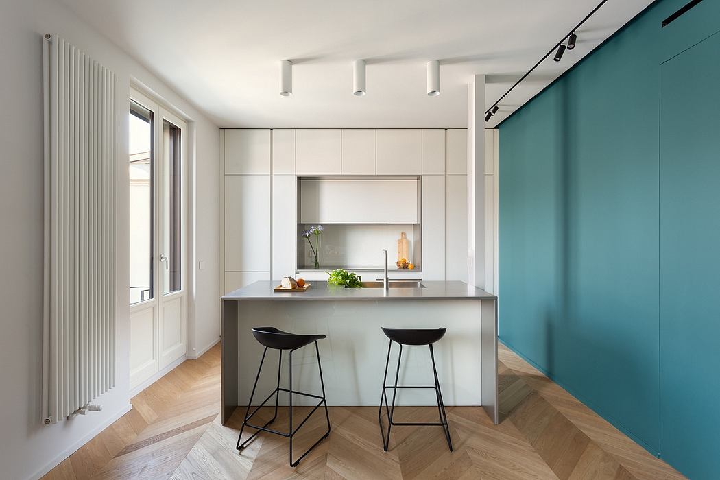Modern, minimalist kitchen with sleek white cabinetry, teal accent wall, and stylish bar stools.