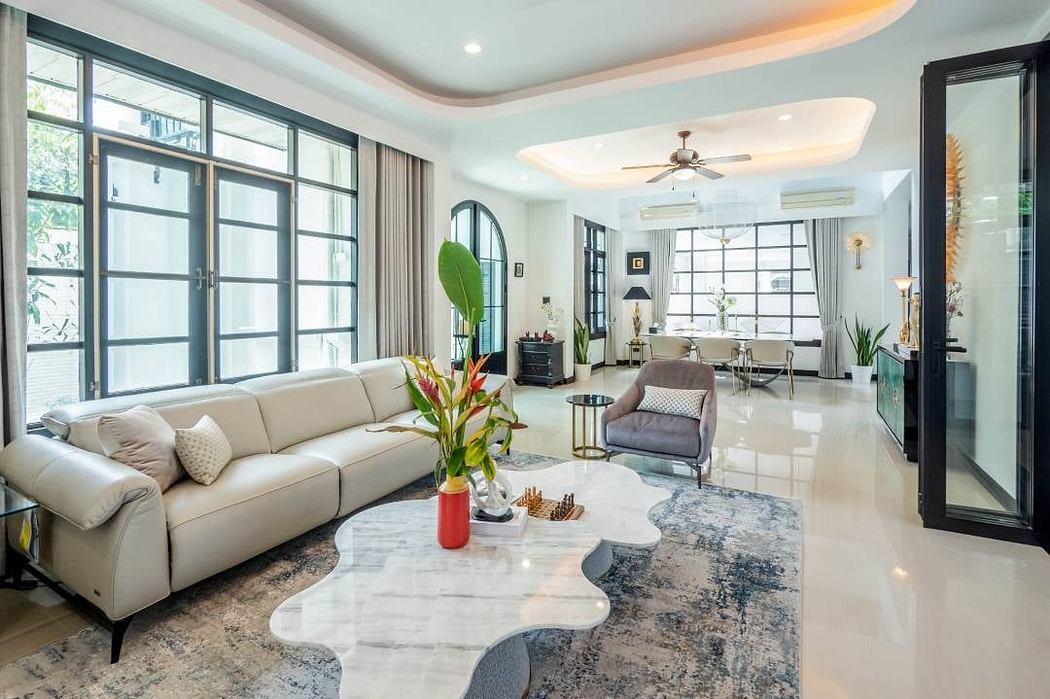 Spacious open-concept living room with large windows, plush sofa, and modern decor.
