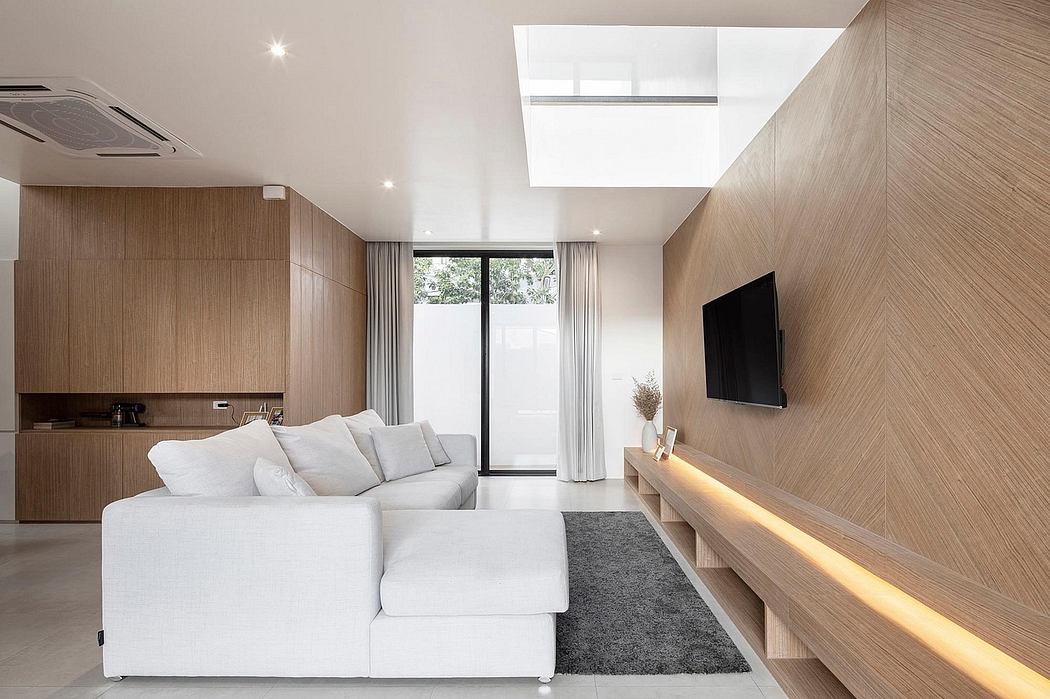 Minimalist living room with wooden walls, white sofa, and recessed lighting.