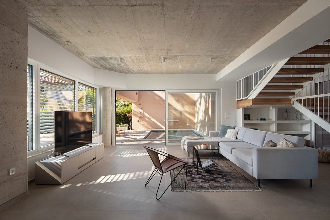 Spacious concrete-ceiling living room with large glass doors, modern furnishings, and natural light.