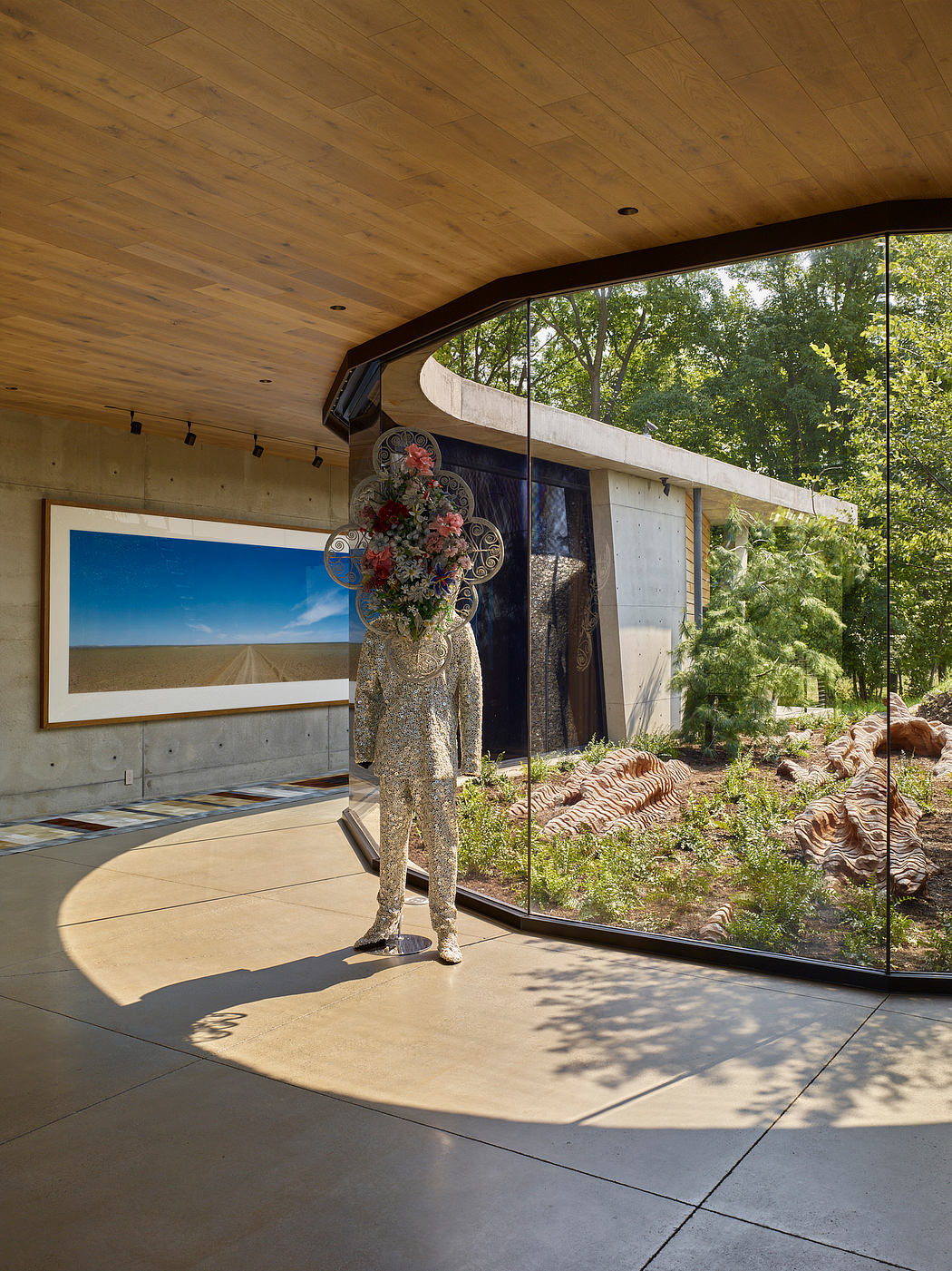 Striking architectural elements, expansive windows, lush greenery, and a whimsical floral sculpture create a visually captivating space.