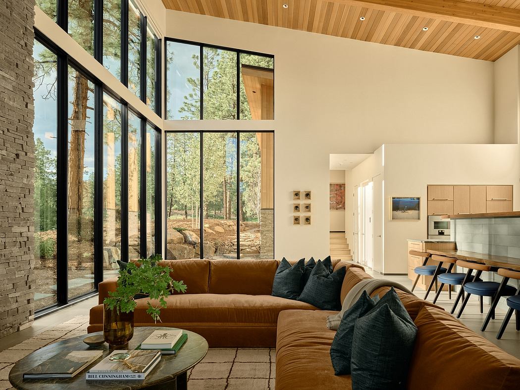 Spacious open-plan living area with floor-to-ceiling windows, wood-paneled ceiling, and modern furniture.