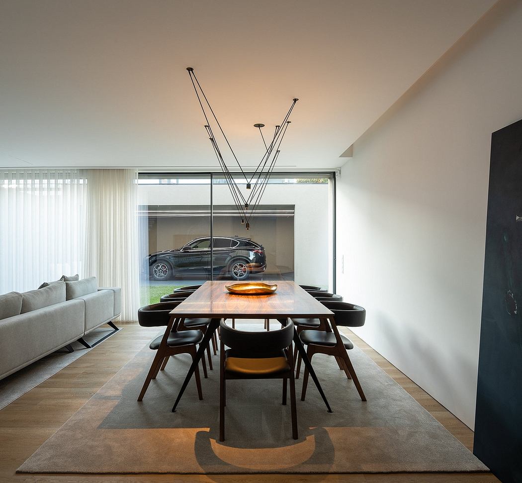 Sleek modern dining room with a large wooden table, black chairs, and a view of a car.
