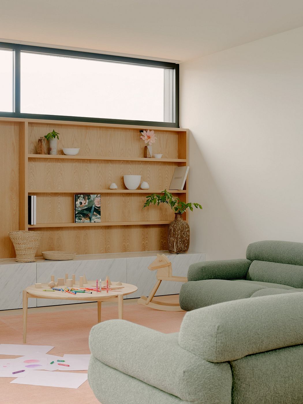 Modern living room with built-in shelving, plush green sofa, and minimalist decor.