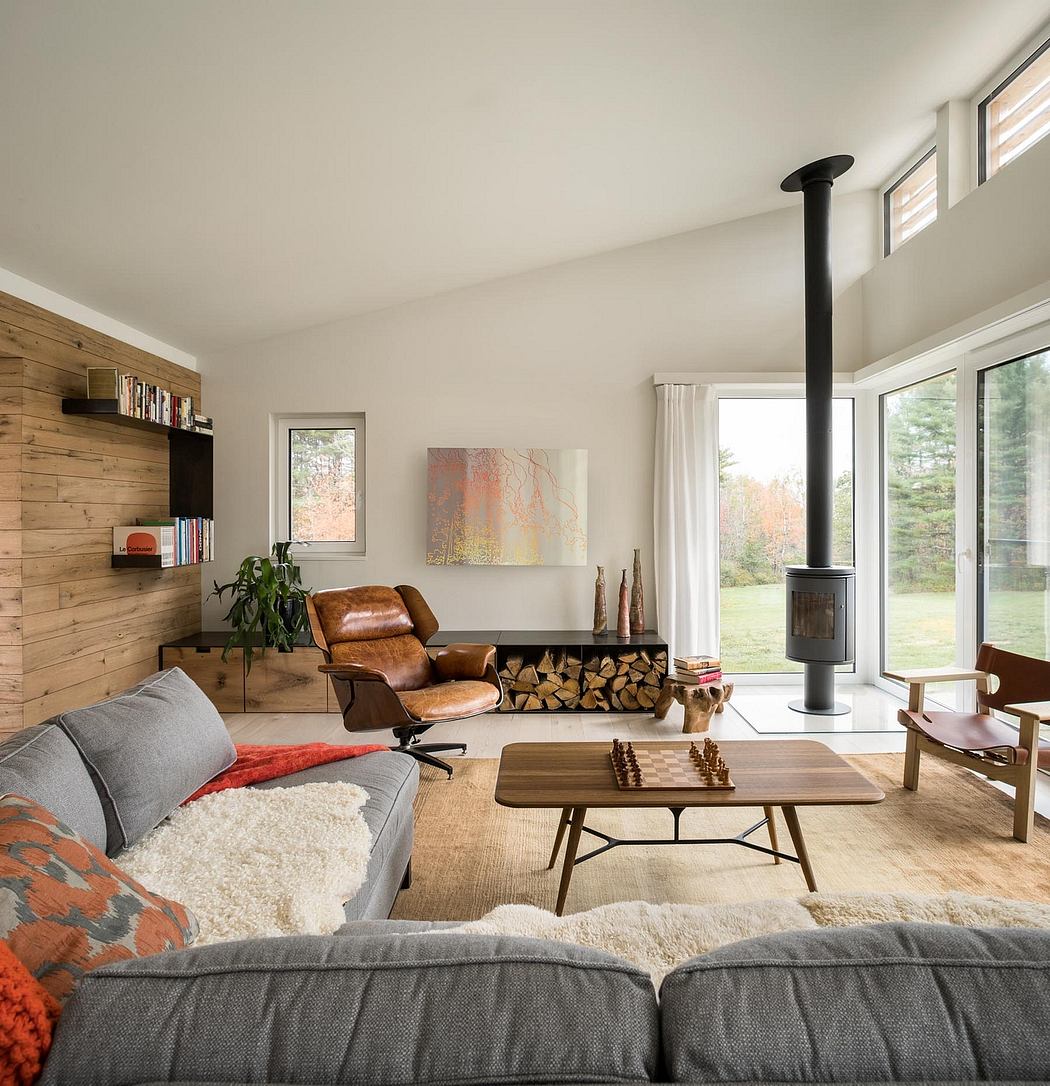 Cozy modern cabin interior with wood paneling, large windows, and minimalist furnishings.