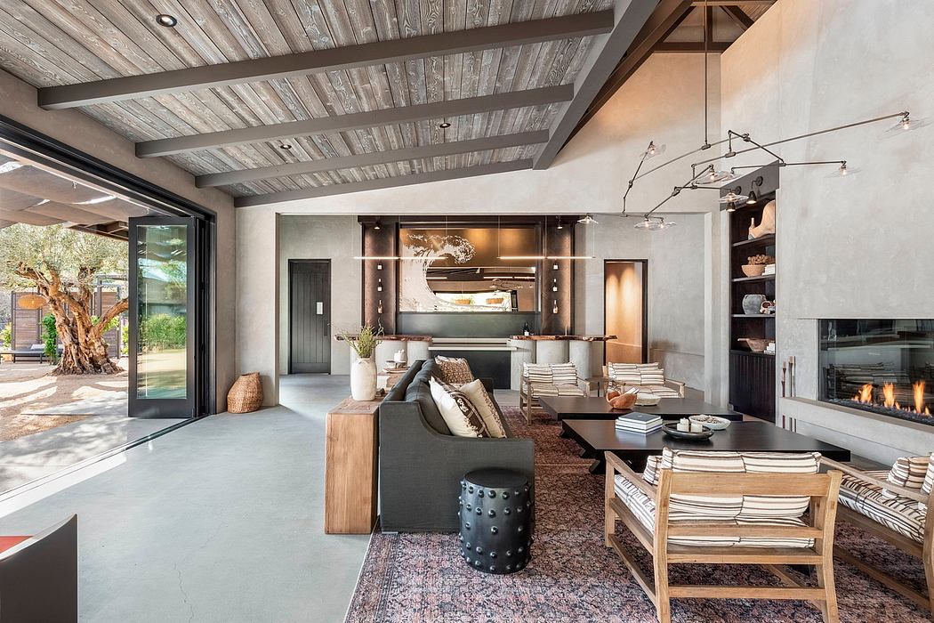 Rustic open-plan living space with wooden ceiling beams, textured stone walls, and modern furnishings.