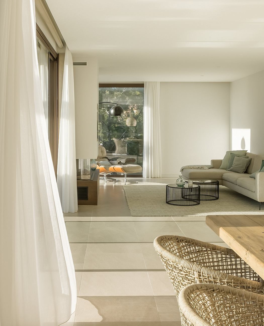 A modern living room with sleek furniture, soft lighting, and large windows overlooking nature.