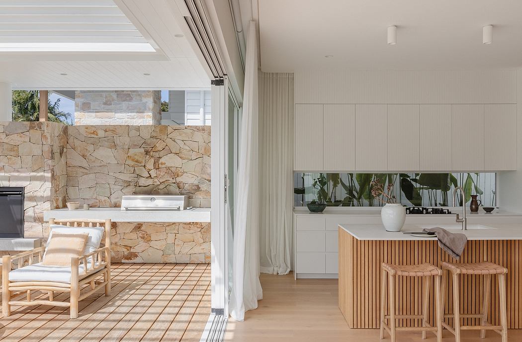 Modern, open-plan kitchen with stone walls, wood finishes, and sliding glass doors leading to outdoor patio.