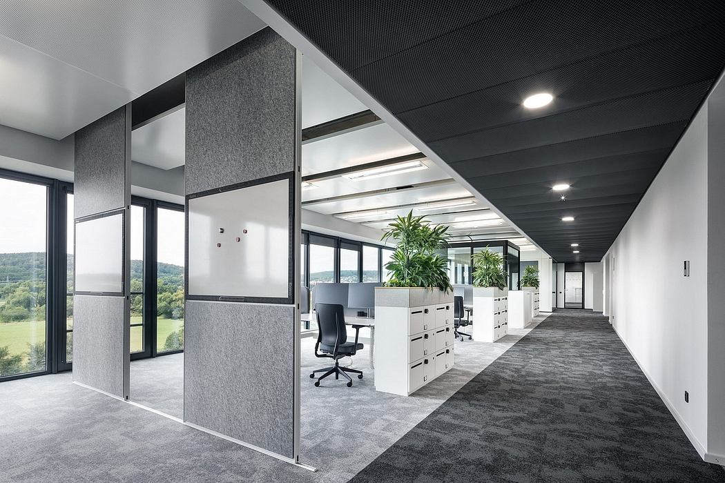 Sleek, modern office space with gray tones, glass walls, and a lush indoor landscape.