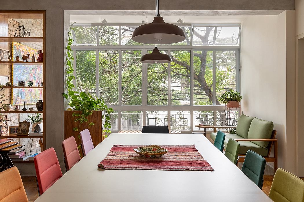 A cozy dining room with large windows, colorful seating, and lush greenery outside.