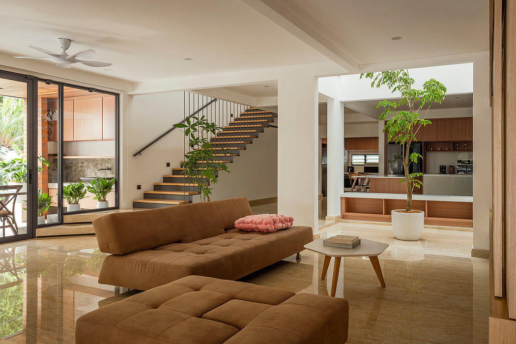 Warm, modern living space with sleek staircase, plush sofa, and potted plants.