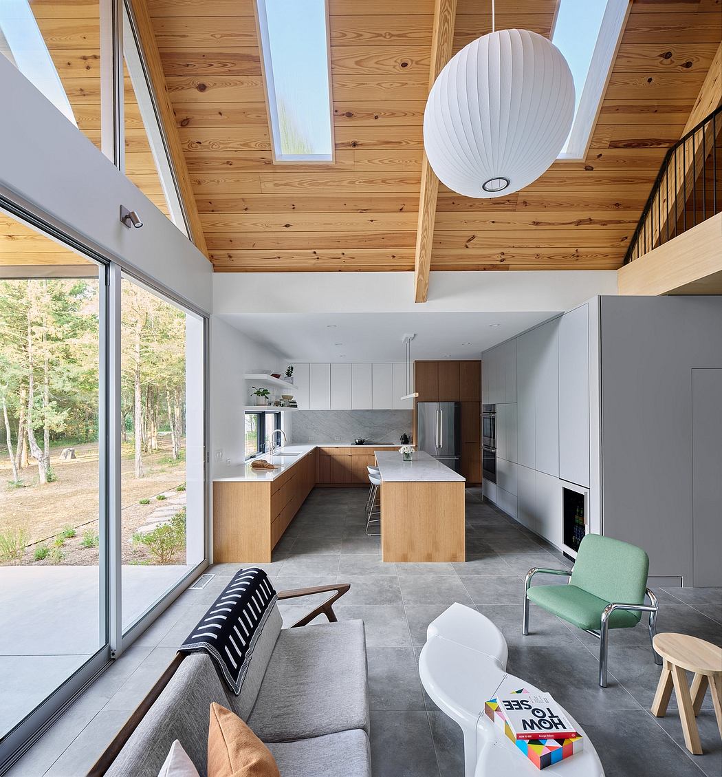 Modern open-plan kitchen with wood-paneled ceiling, large windows, and custom cabinetry.