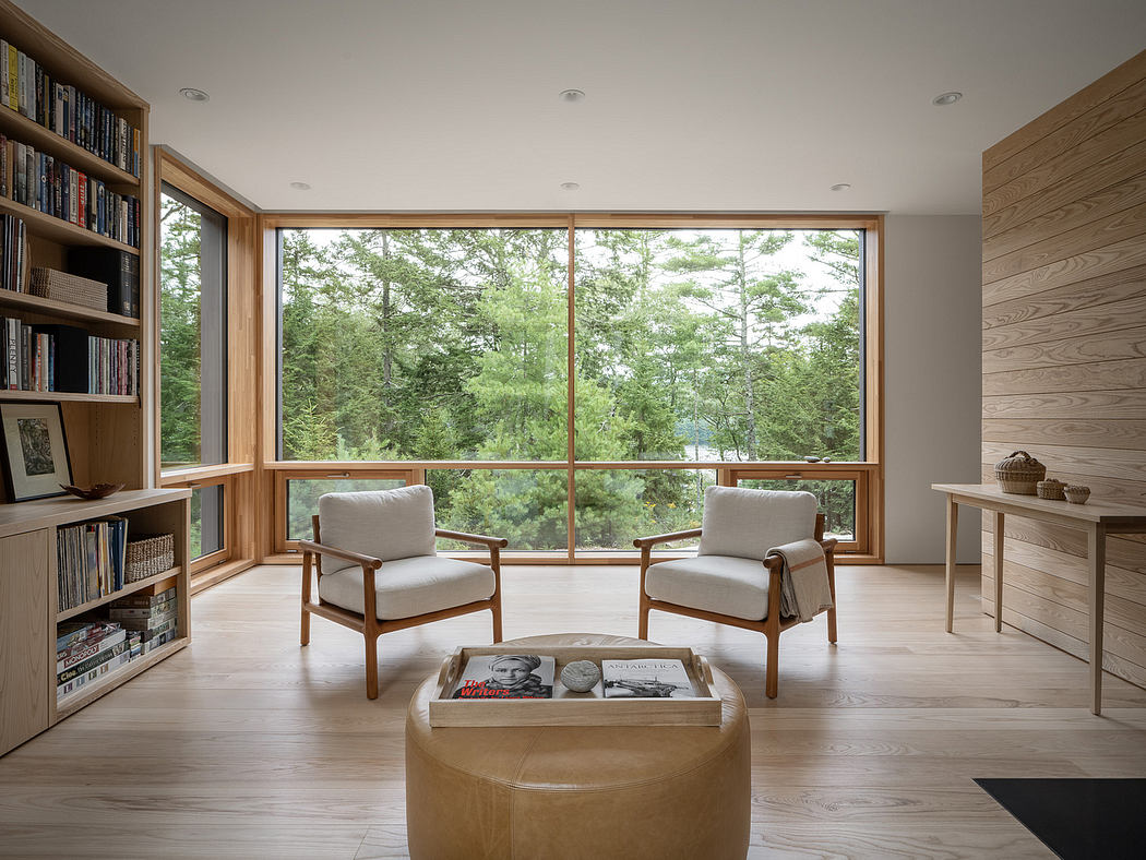 A contemporary living room with floor-to-ceiling windows overlooking a wooded landscape.