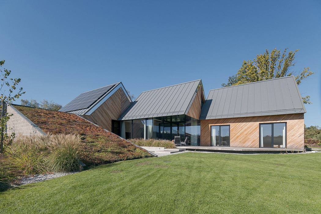 Modern, multi-level home with angular roofs, wooden siding, and expansive glass windows.