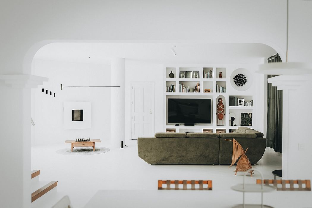 Minimalist living room with built-in shelving, TV, and seating in neutral tones.