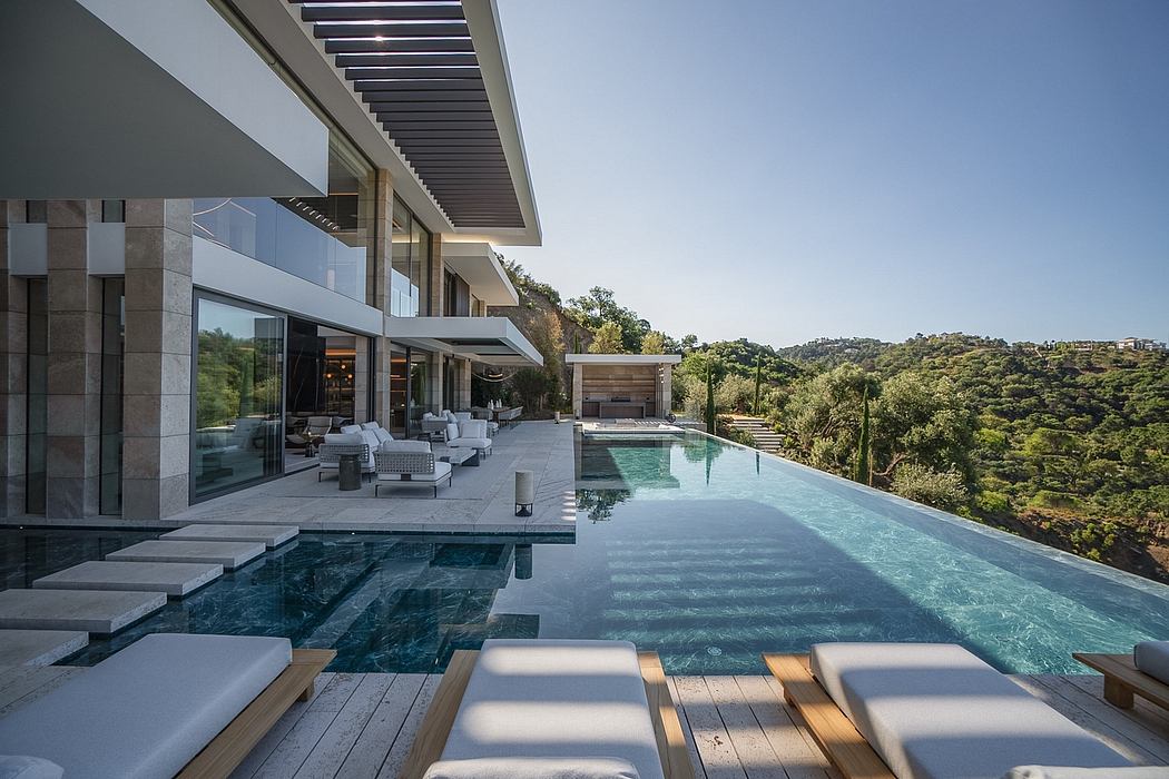 Sleek modern architecture with an expansive outdoor pool and patio area overlooking lush greenery.