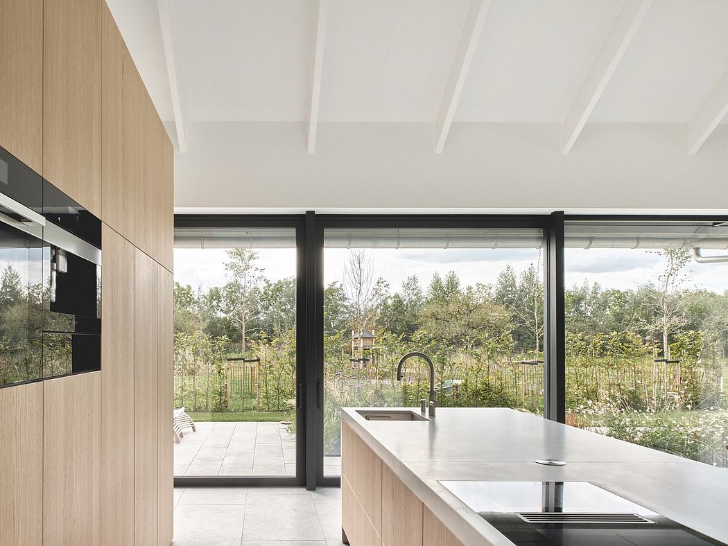 Spacious open-plan kitchen with floor-to-ceiling glass doors overlooking lush garden.