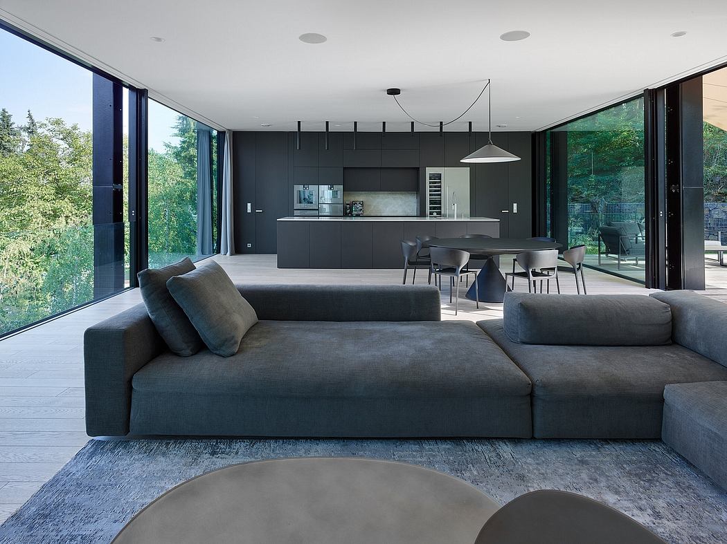 Sleek, modern interior with black and gray tones, large windows, and an open-concept layout.