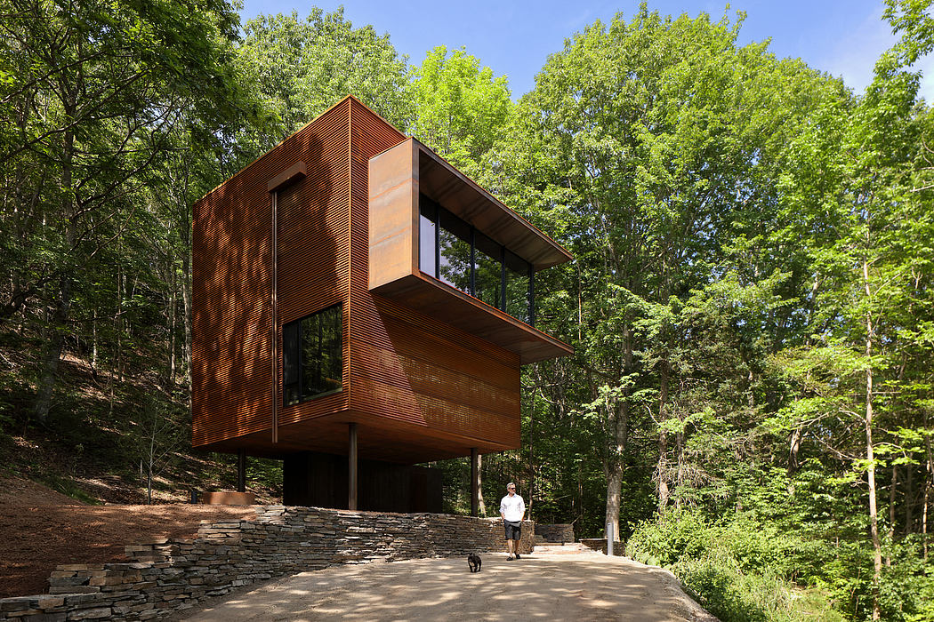 A modern, wooden cabin-like structure nestled in a lush, green forest setting.