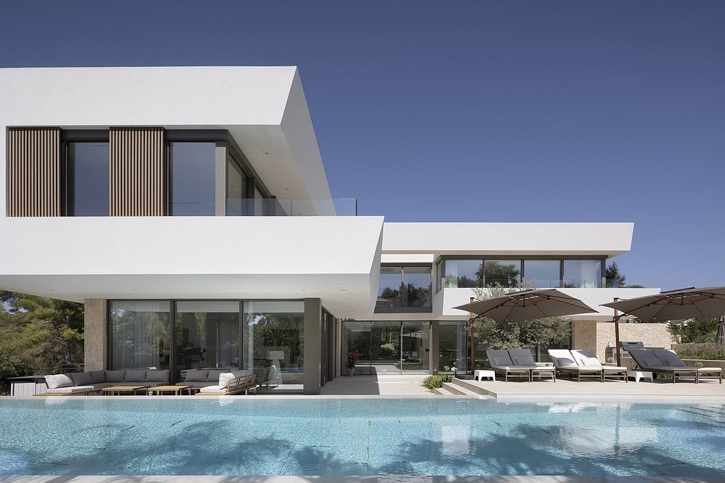Modern minimalist villa with sleek architectural features, large glass panels, and an inviting poolside terrace.