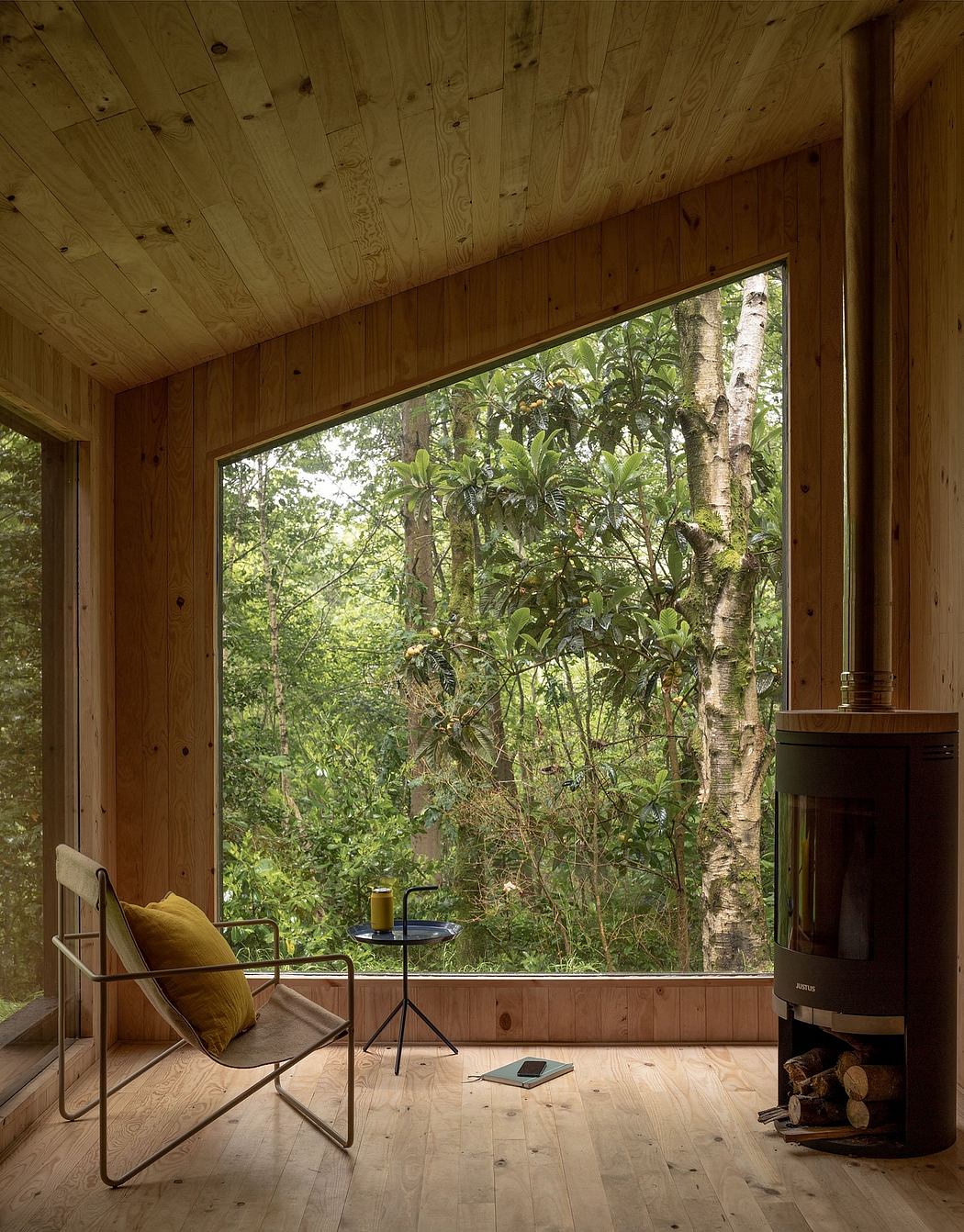 A cozy wooden cabin interior with a large window overlooking a lush forest landscape.
