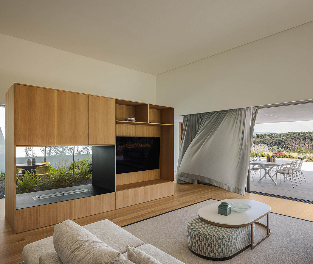 A spacious living room with a wooden media cabinet, sliding glass doors, and neutral furnishings.